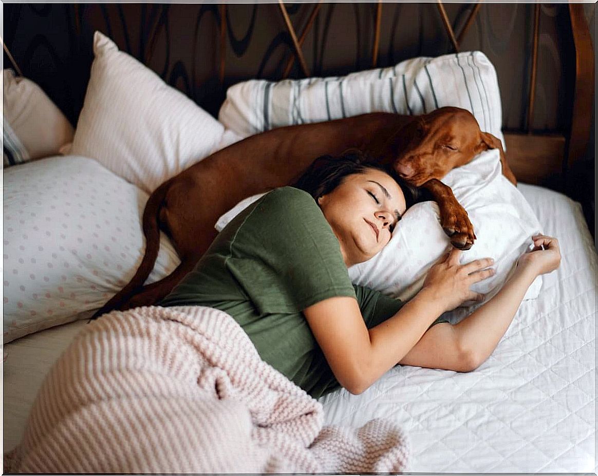 A girl sleeps with her dog.